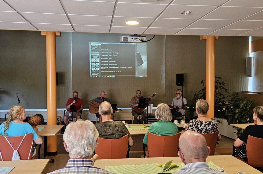 Bezoekers zingen mee met de Parkinson Meezingband tijdens het Parkinson Meezingcafé.