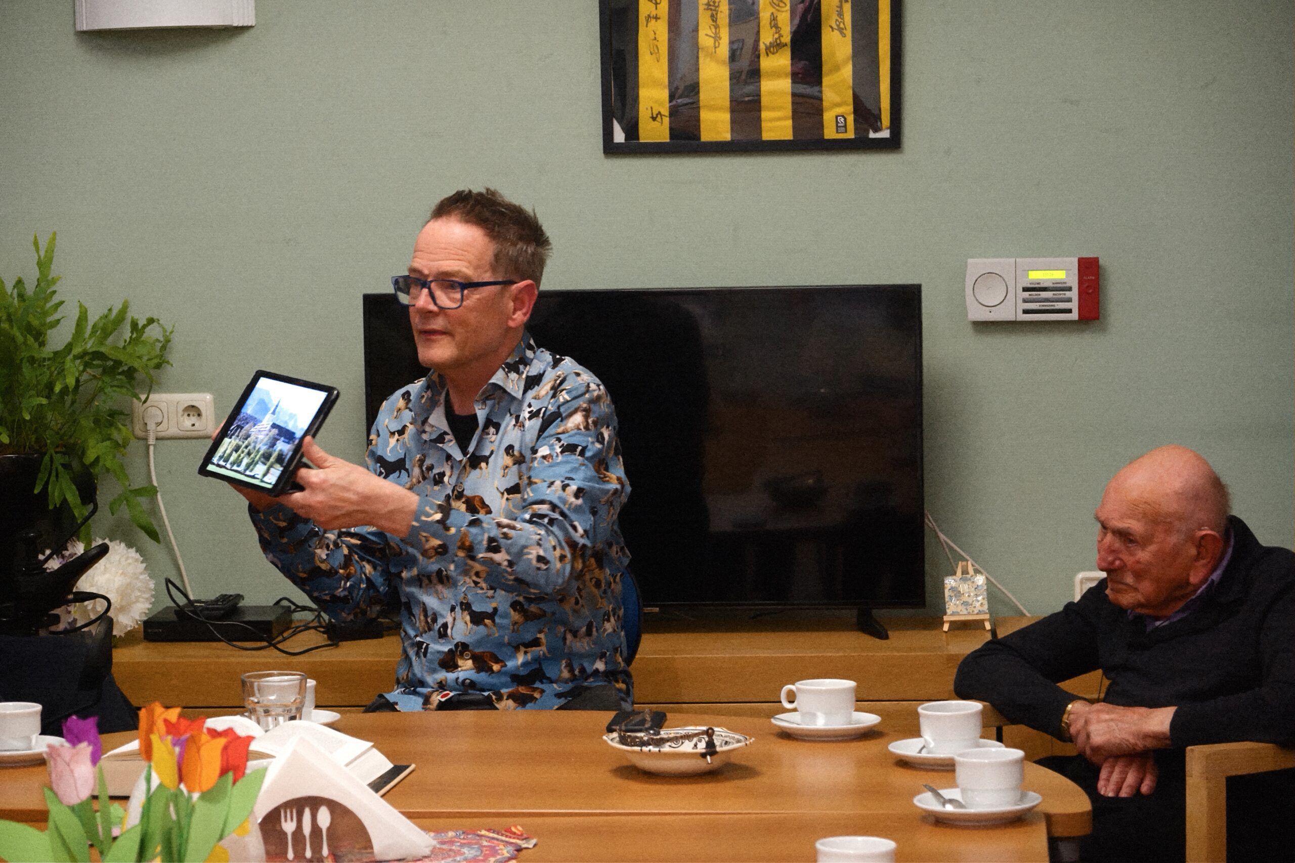Walter Jansen toont zijn e-reader tijdens de voorleesavond op Insula Dei.
